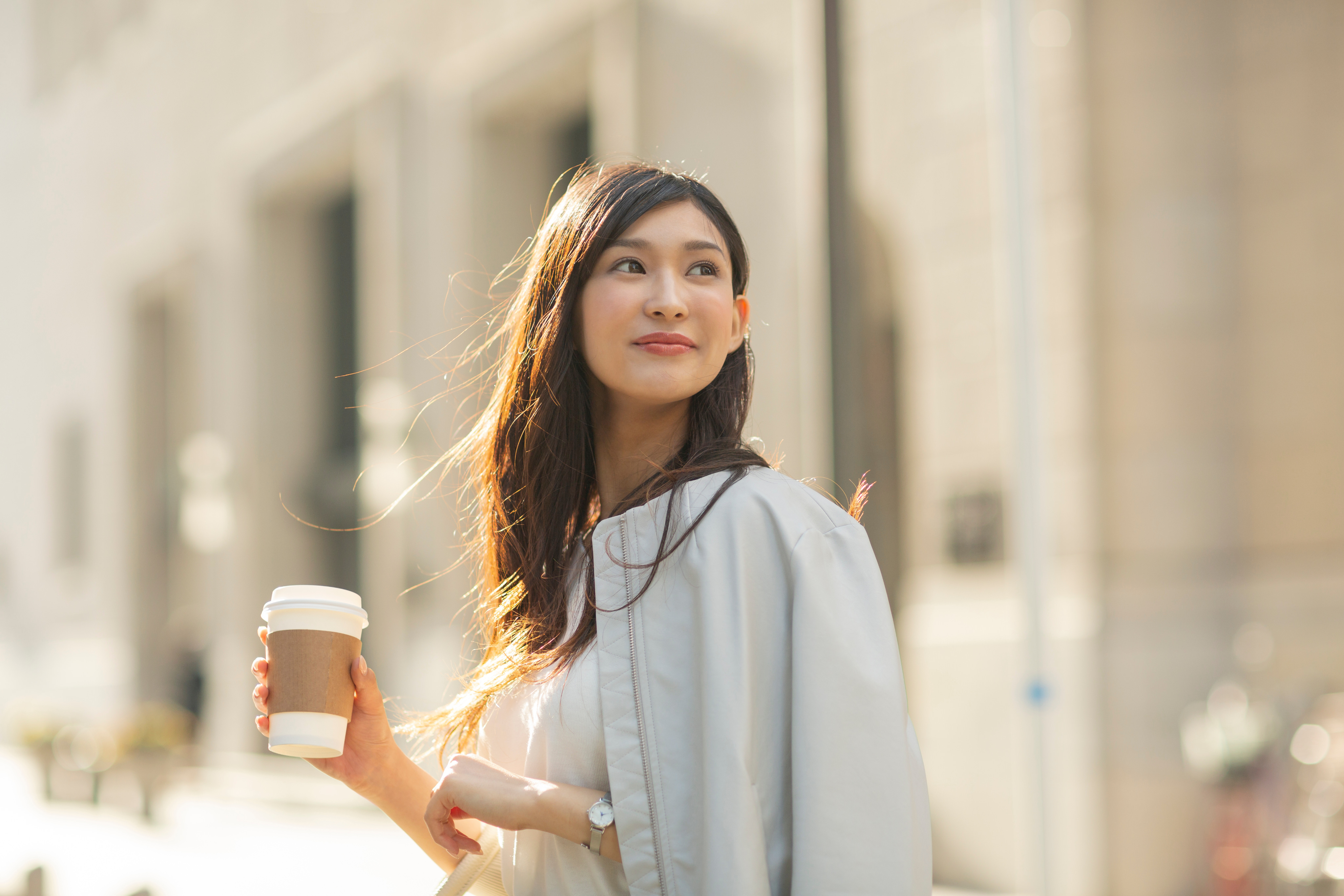 コーヒーを手に街を見上げる女性